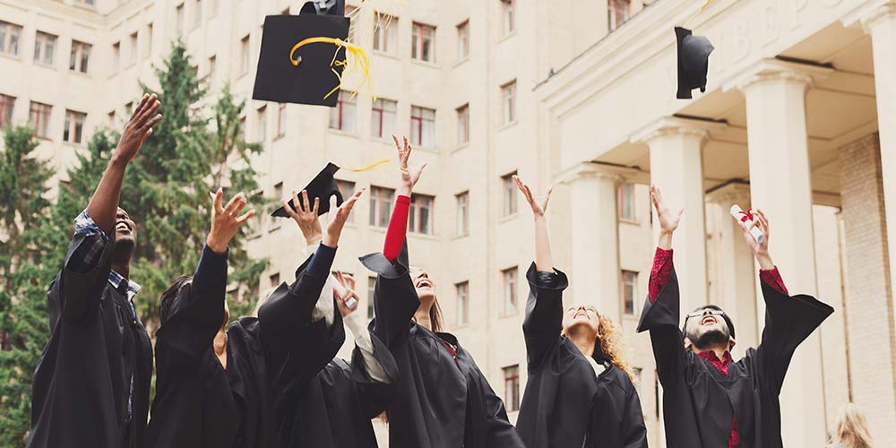 A group of law school graduates throw their caps in the air to celebrate their graduation