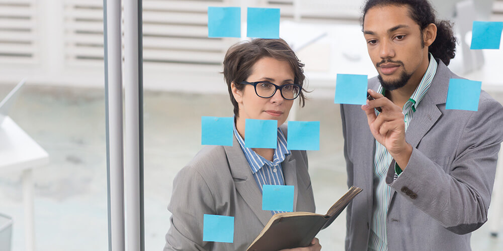 Two professionally-dressed lawyers discuss a list of reminders for their next remote deposition.
