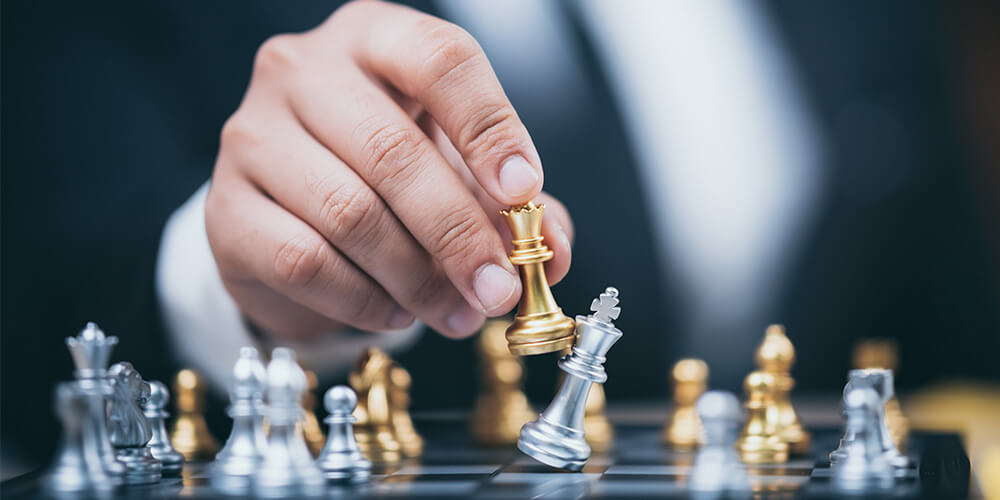 Photo of a man’s hand taking his opponent’s king on the chess board, illustrating the concept of dealing with uncooperative opposing counsel during discovery.