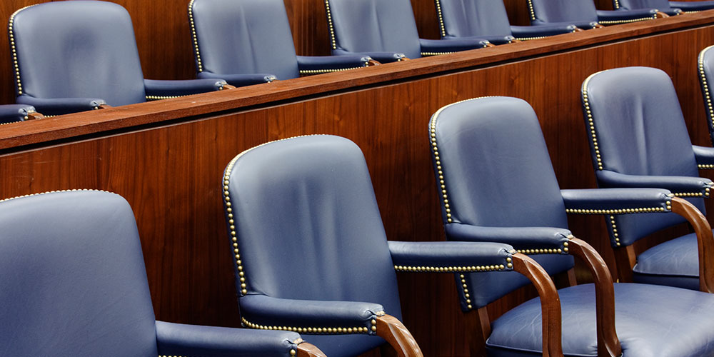 Photo of empty jury seats in a courtroom, illustrating the concept of voir dire for remote trials.