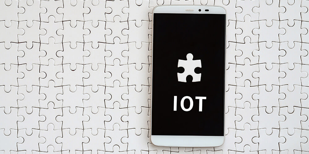 Concept photo of a puzzle board and a puzzle piece labeled ‘IoT’ illustrates how IoT fits in the legal industry.