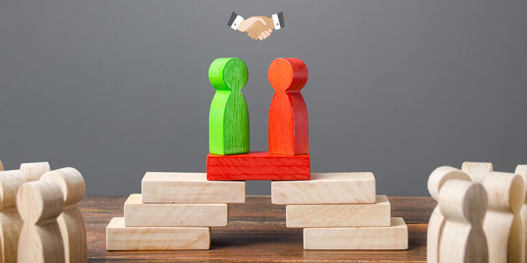 Concept photo showing humanoid wooden blocks forming a bridge between each other with an icon of a handshake above their heads - illustrating eDiscovery protocol negotiation