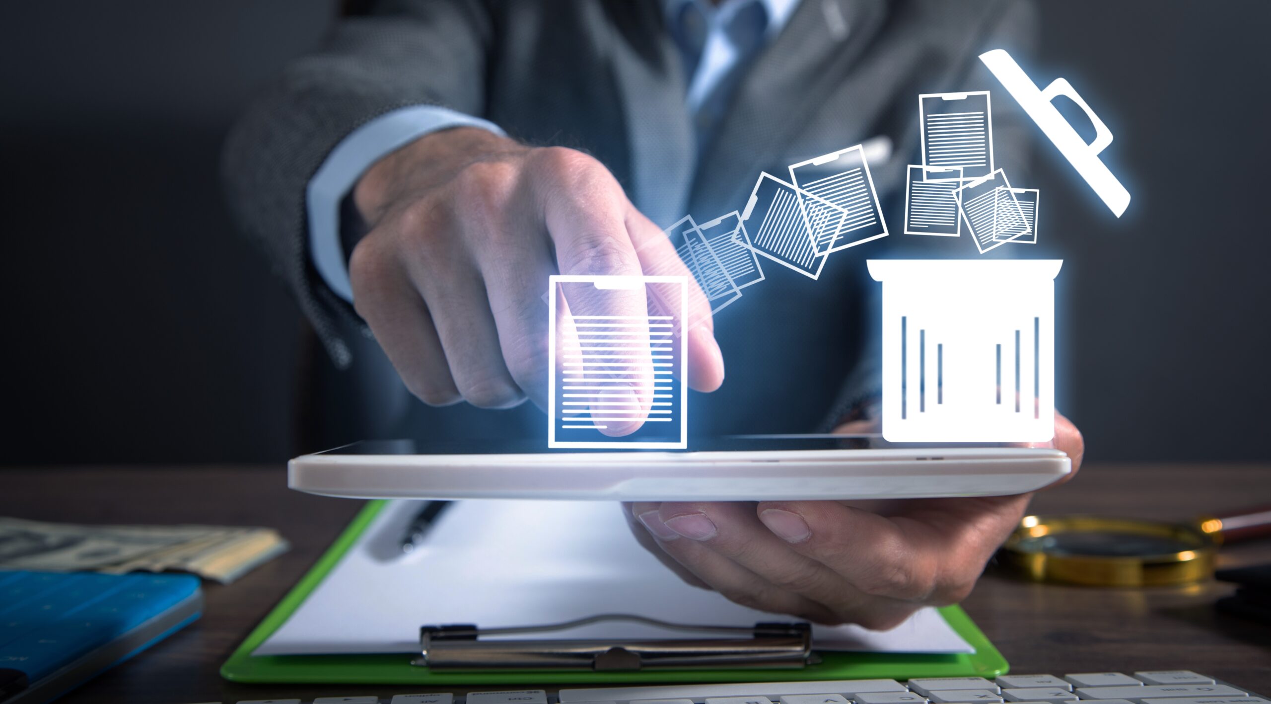 Business professional using a tablet to interact with a holographic projection of documents transitioning into a trash bin symbol, indicating digital data deletion or management.